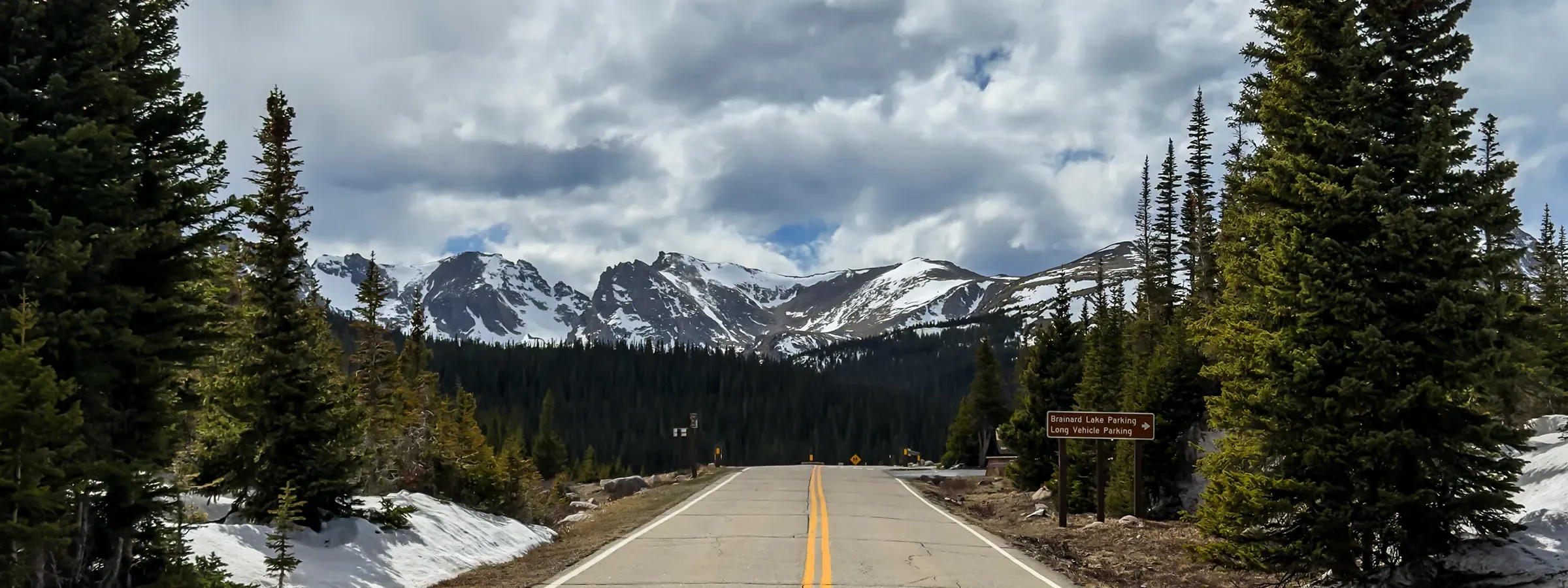 Empty mountain road leading to snow-capped peaks