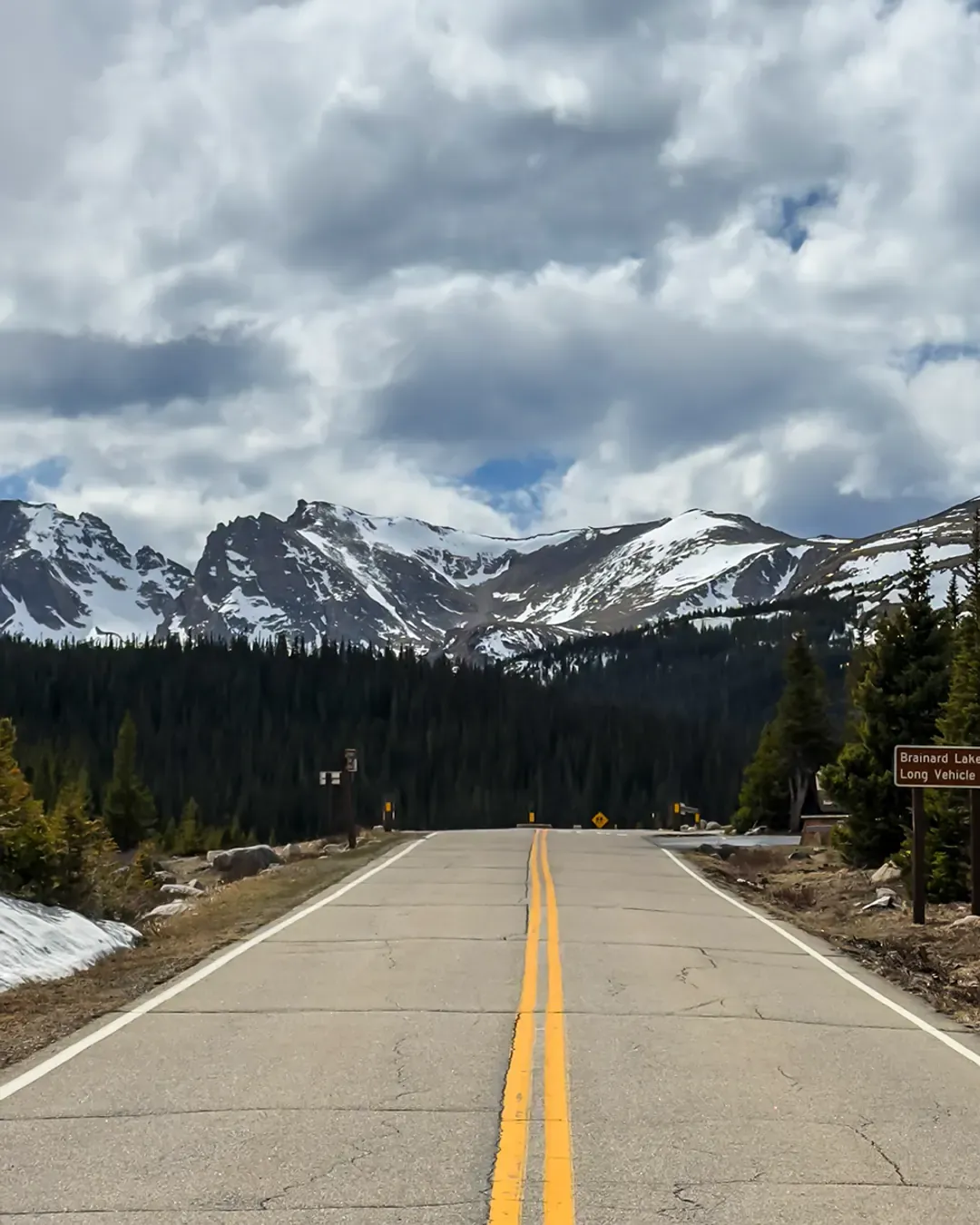 Empty mountain road leading to snow-capped peaks