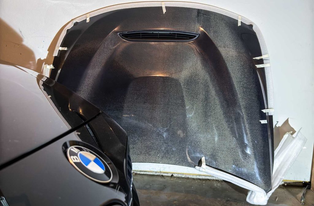 bmw carbon fiber hood next to a bmw m4